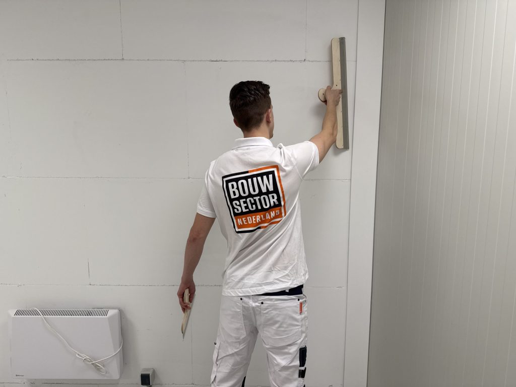 Stukadoor van Bouwsector Nederland reikt met een spaan naar het bovenste deel van een wand